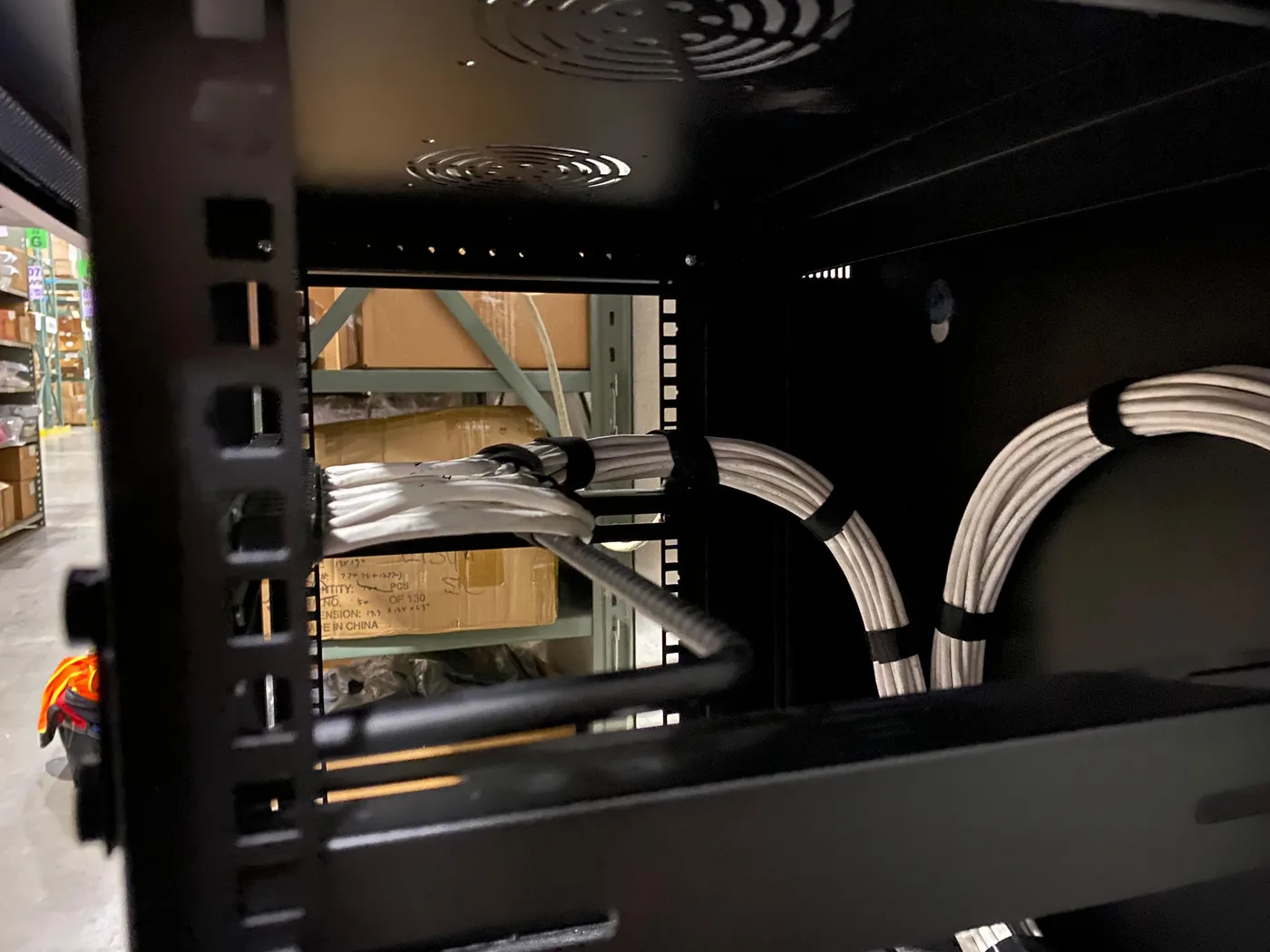 Cable loops are routed and secured inside a network cabinet while keeping the equipment area accessible.